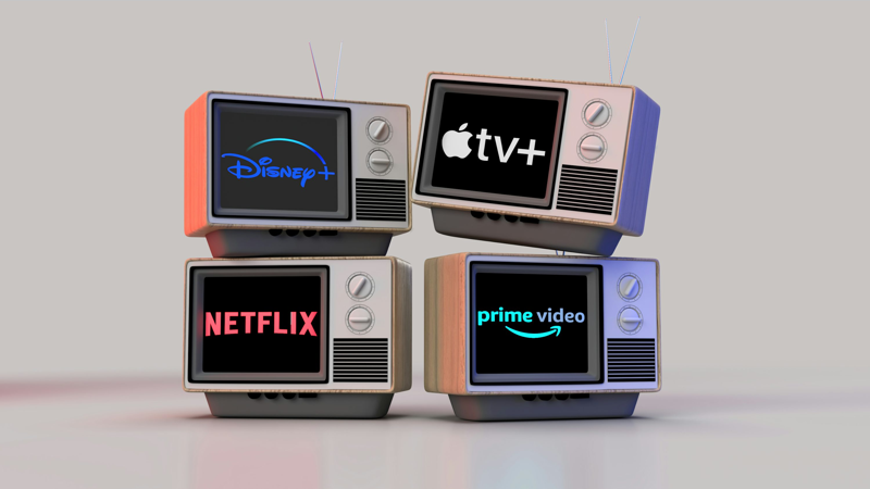 A detailed illustrative image of four stylized retro televisions stacked on a gray background, each screen clearly displaying the logo of a different major streaming service: Disney+, Apple TV+, Netflix, and Amazon Prime Video.