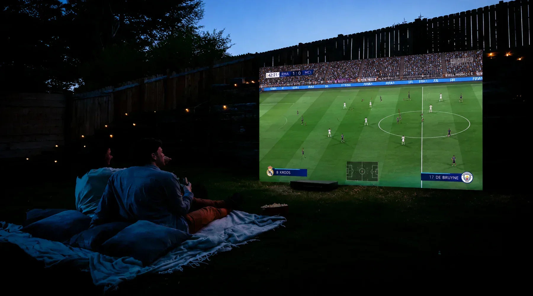 Backyard soccer watch party with a large outdoor projector screen.