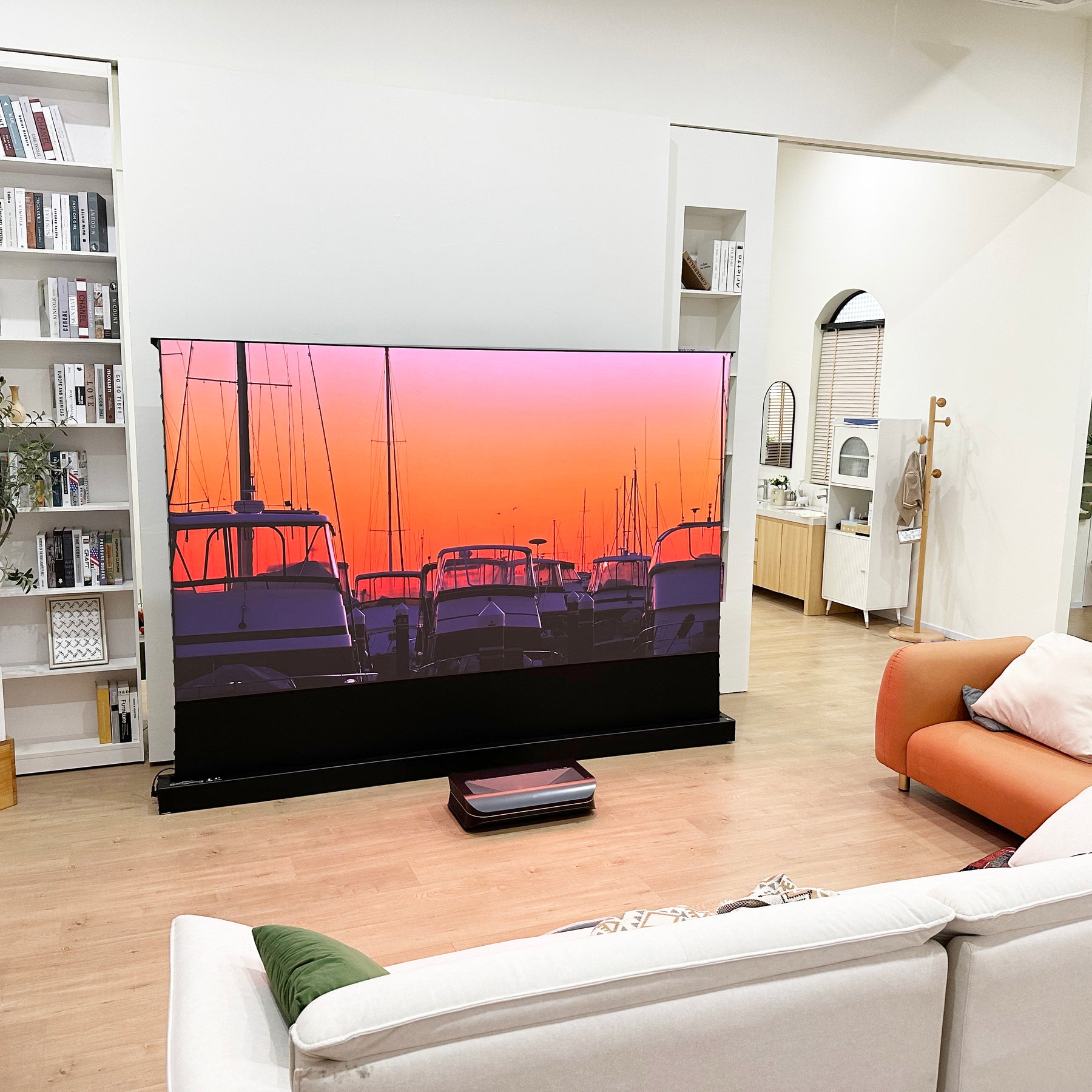 AWOL Vision Cinematic + ALR floor rising  projector screen in a modern living room showing an image of a ship at sunset, creating an elegant home decoration.