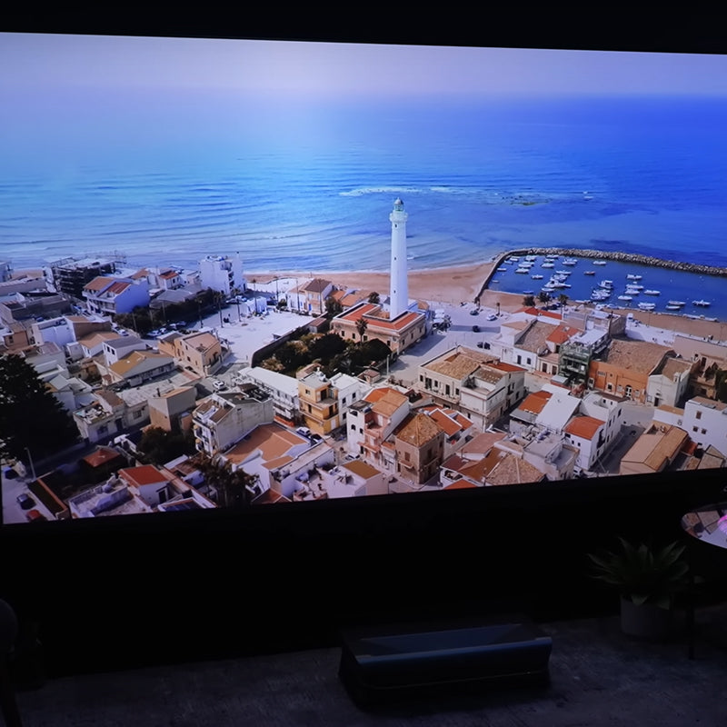 Cinematic+ ALR floor rising projector screen featuring a beautiful beach scene, perfect for immersive home cinema setups.