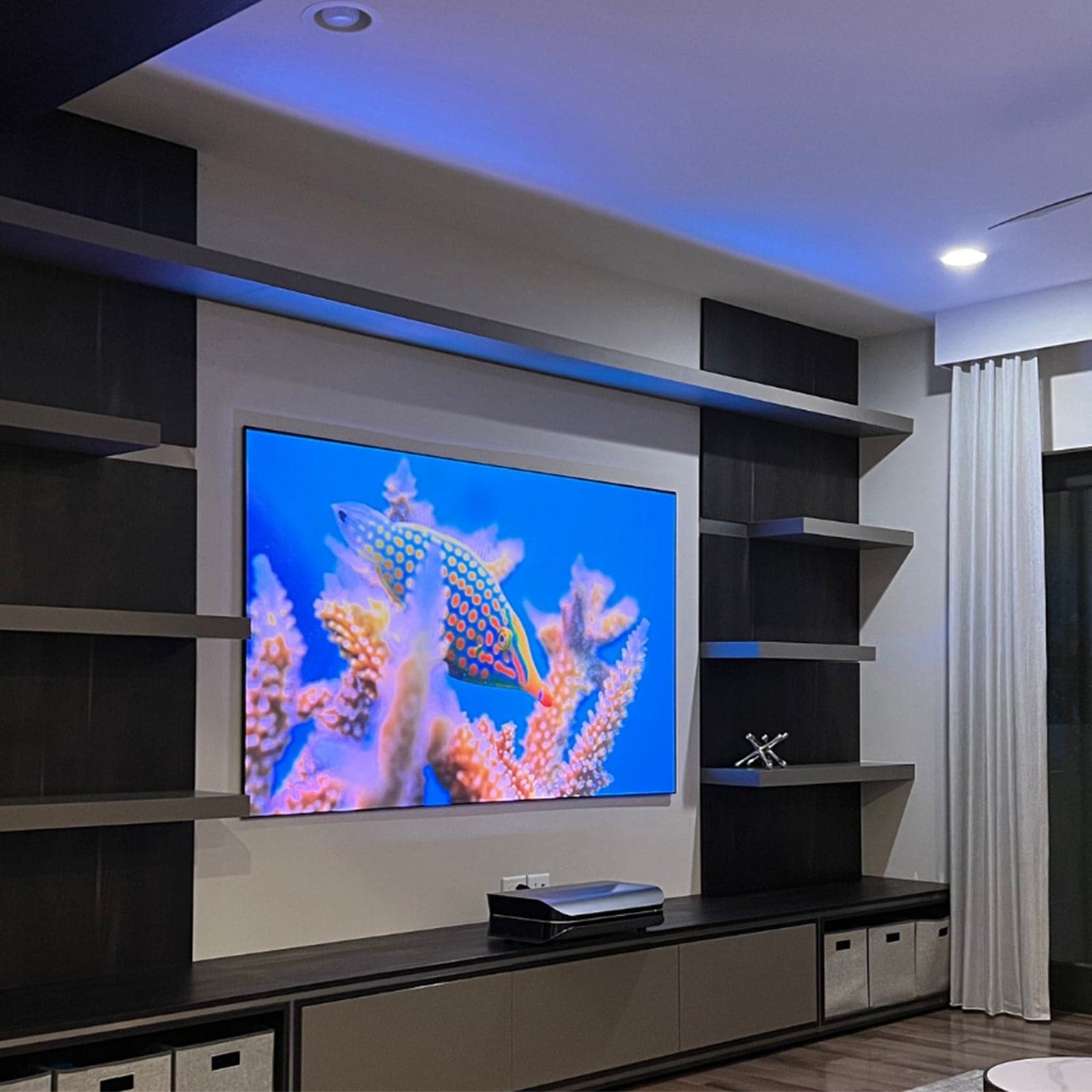 A modern living room featuring LTV-2500 Dolby Atmos Projector with a vibrant underwater scene on the screen.