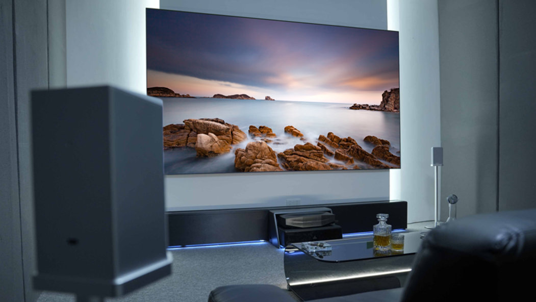A modern home theater room featuring a large screen and freestanding speakers, demonstrating a typical high-end setup that requires proper acoustic treatment to prevent muddy sound.
