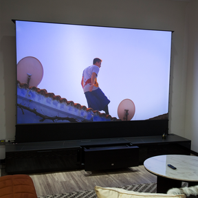 AWOL Vision Laser TV in a home setting showcasing a captivating scene of a man on a rooftop, displayed on a vast motorized screen that complements the sleek living room decor.