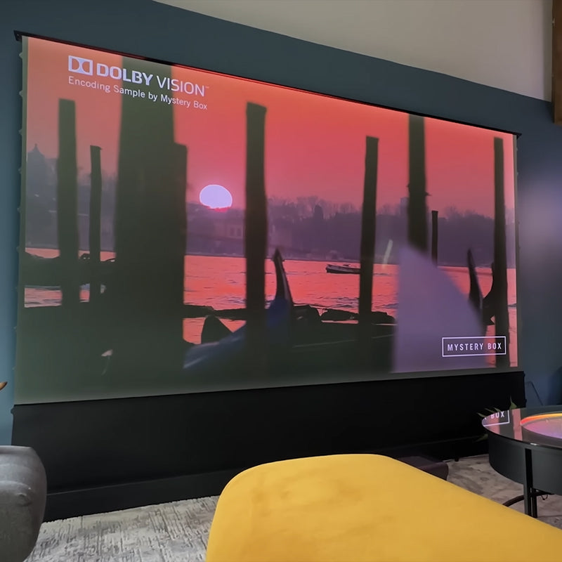 AWOL Vision Cinematic+ ALR motorized projector screen displaying a sunset scene in Dolby Vision quality.