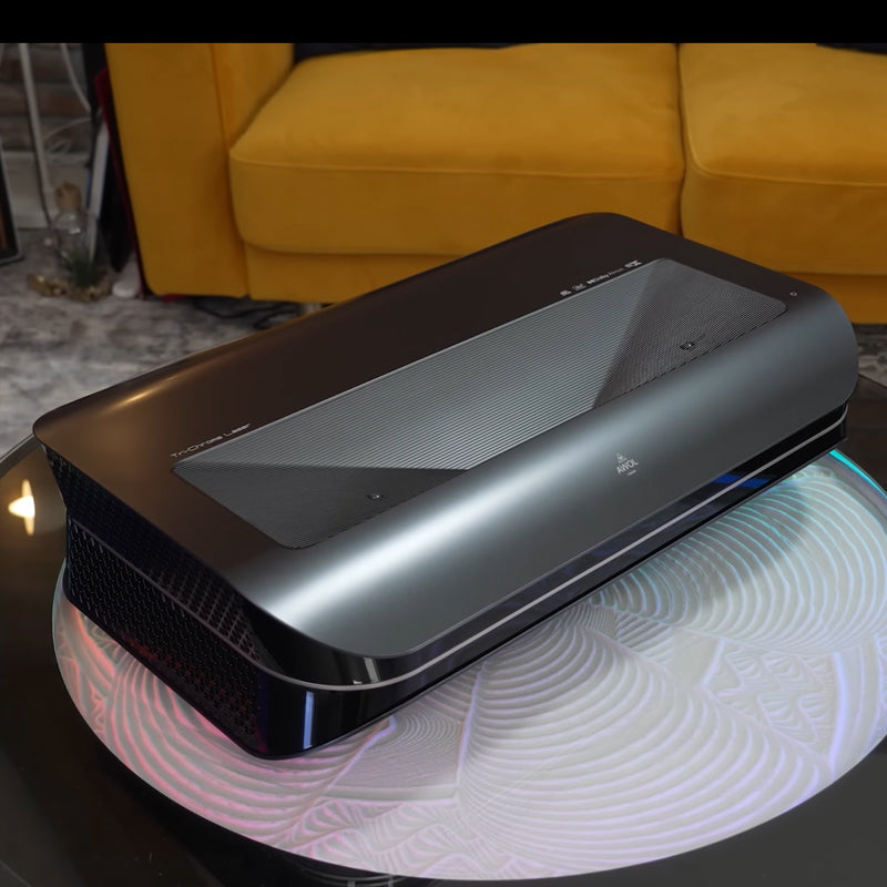 AWOL Vision LTV-3500 Pro 4K 3D Triple Laser Projector displayed in a modern living room, highlighting its elegant design and sophisticated color gradient.